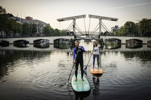 Stehplatz in Amsterdam: Die Boards, die hier vor der Mageren Brücke dahingleiten, sind 3,50 m lang. Toruguide Morene Dekker (re.) hat den Trend Stand-up-Paddle nach Amsterdam gebracht. Sie führt Autor Janek Schmidt durch die Stadt. 